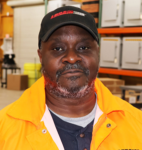 A man in a baseball cap stands in a warehouse