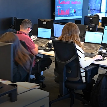 A man and a woman sit at their desks working on computers in an office.