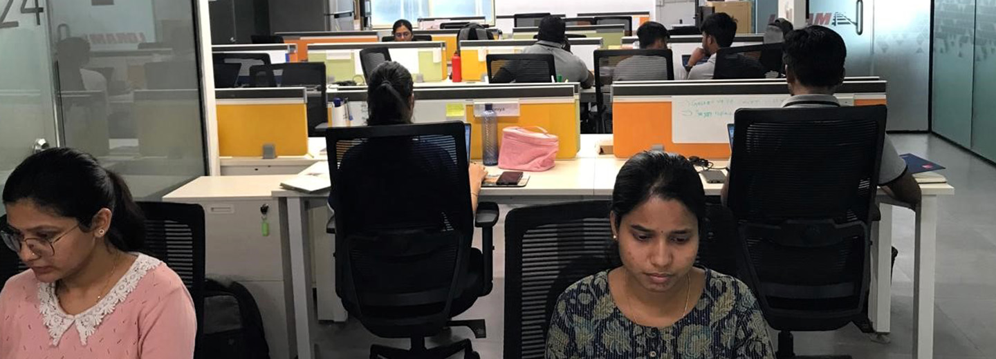 A group of people work at cubicles in an office.